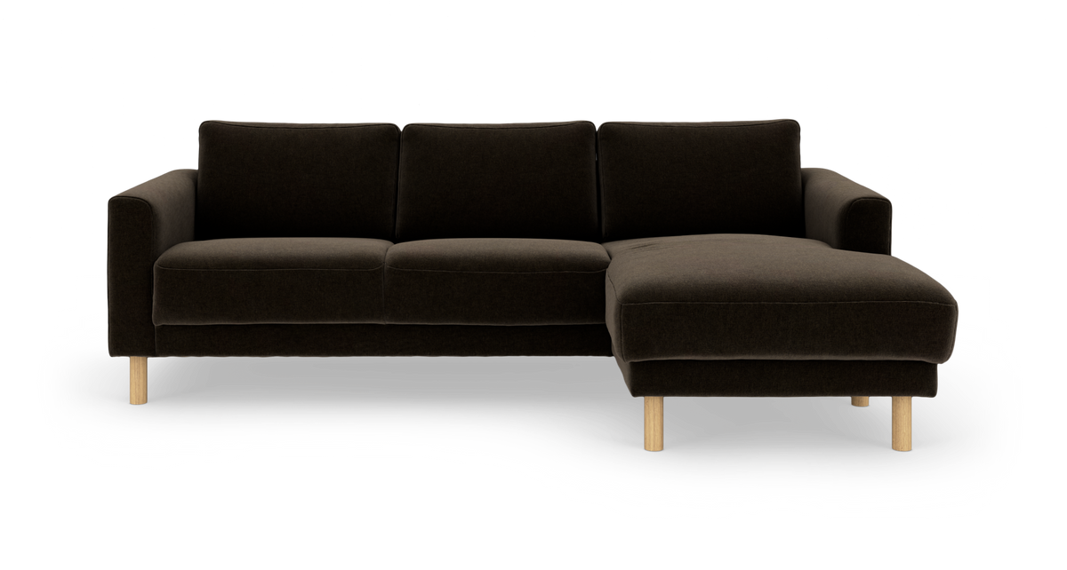Mørkebrun 3-personers sofa med chaiselong til højre og lyse træben, frilagt frontvisning.