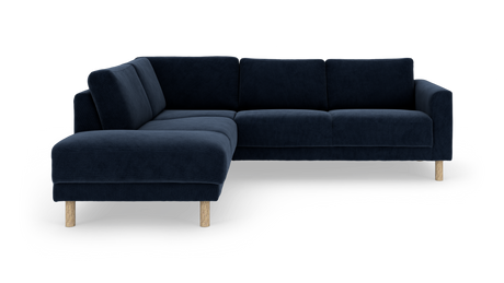 Mørkeblå hjørnesofa med bløde puder og lyse træben, frilagt på hvid baggrund.