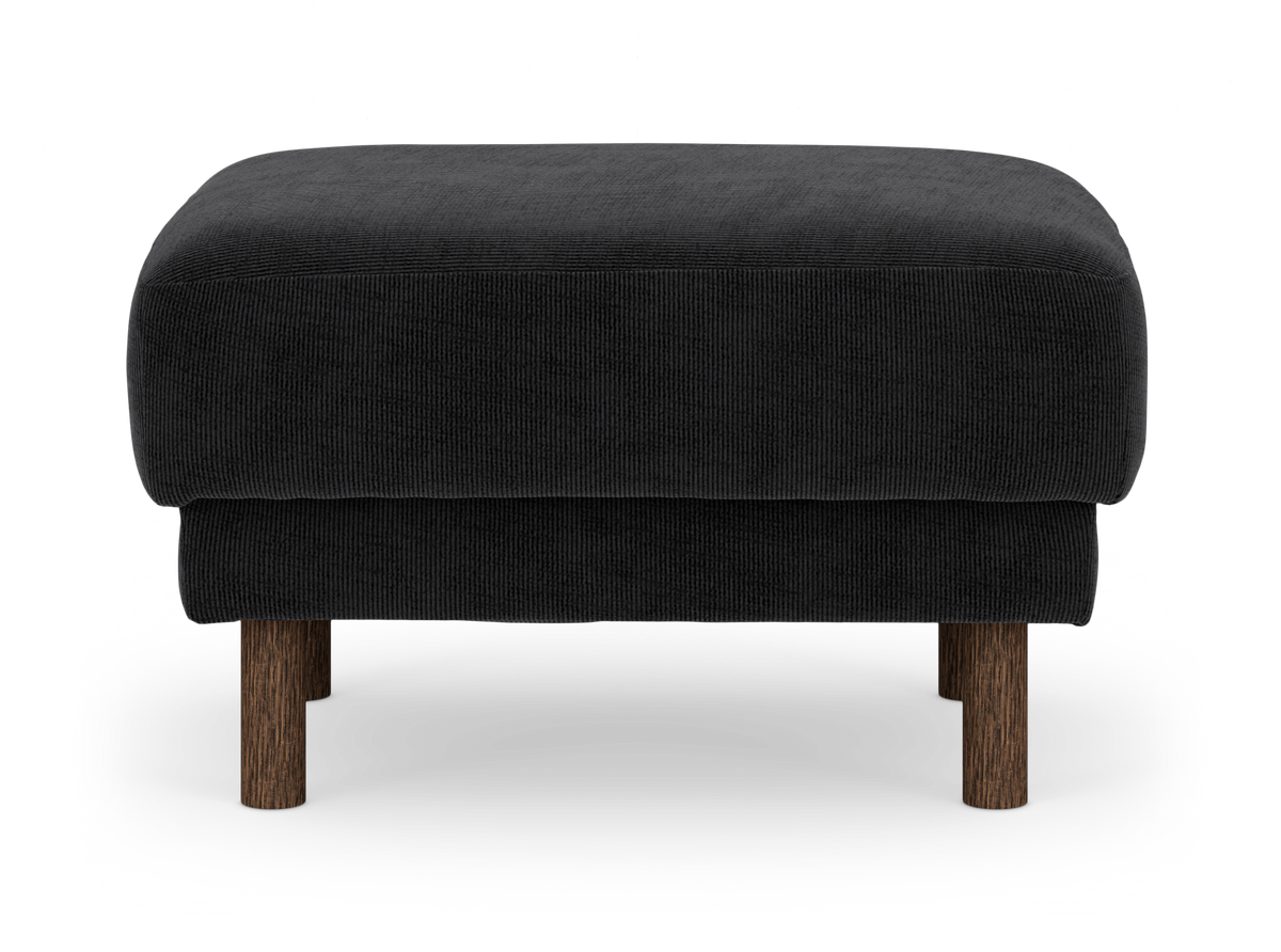 Sort fløjl/stoff-ottoman med runde mørke træben, frilagt på hvid baggrund.