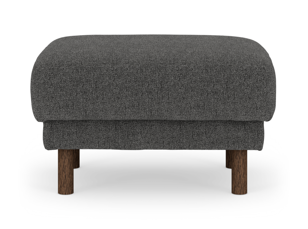 Mørkegrå stofpuf/ottoman med runde træben i mørk brun finish, frilagt på hvid baggrund.