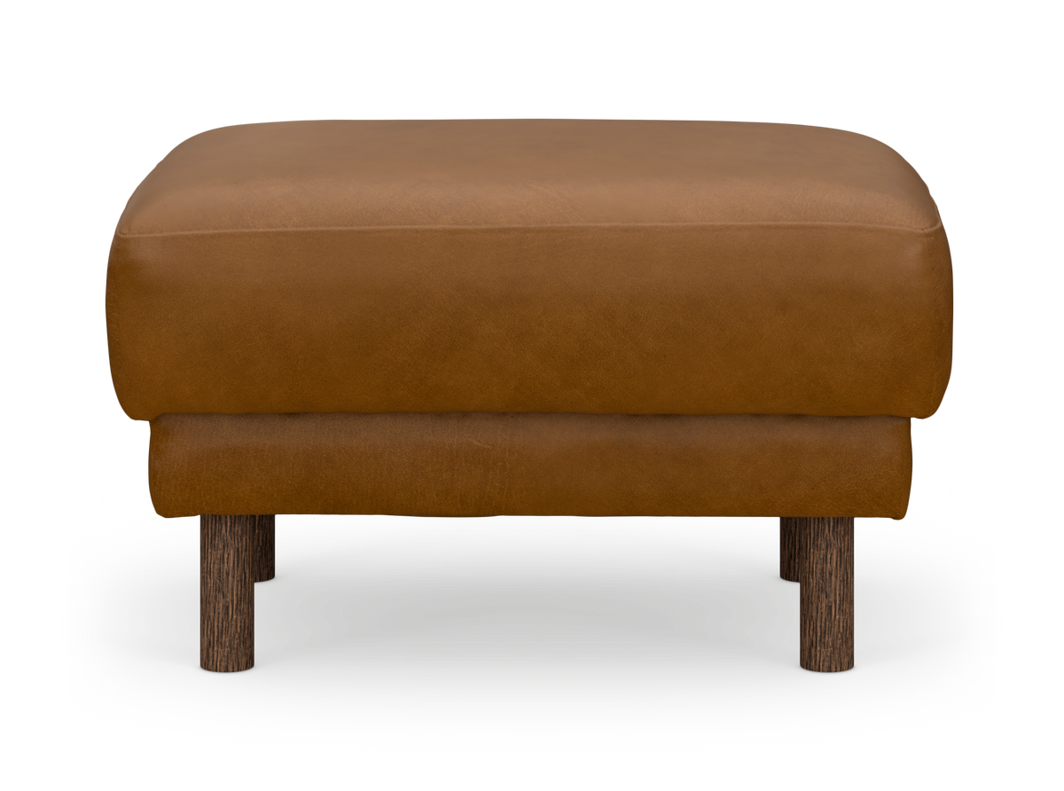Brun læder-ottoman/puf med runde mørke træben, frontvisning mod hvid baggrund.