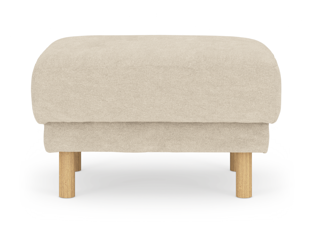 Beige puf i stof med runde ben i lyst træ, frilagt på hvid baggrund.