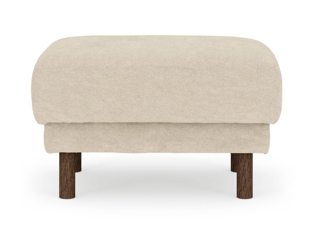 Beige polstret ottoman med runde ben i mørkt træ, frilagt på hvid baggrund set forfra.