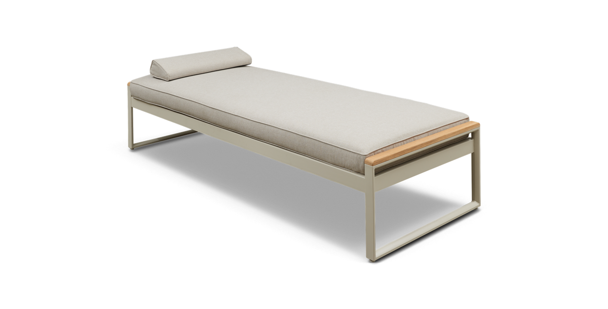 Beige daybed med slank metalramme, trædetaljer og cylinderformet pude.