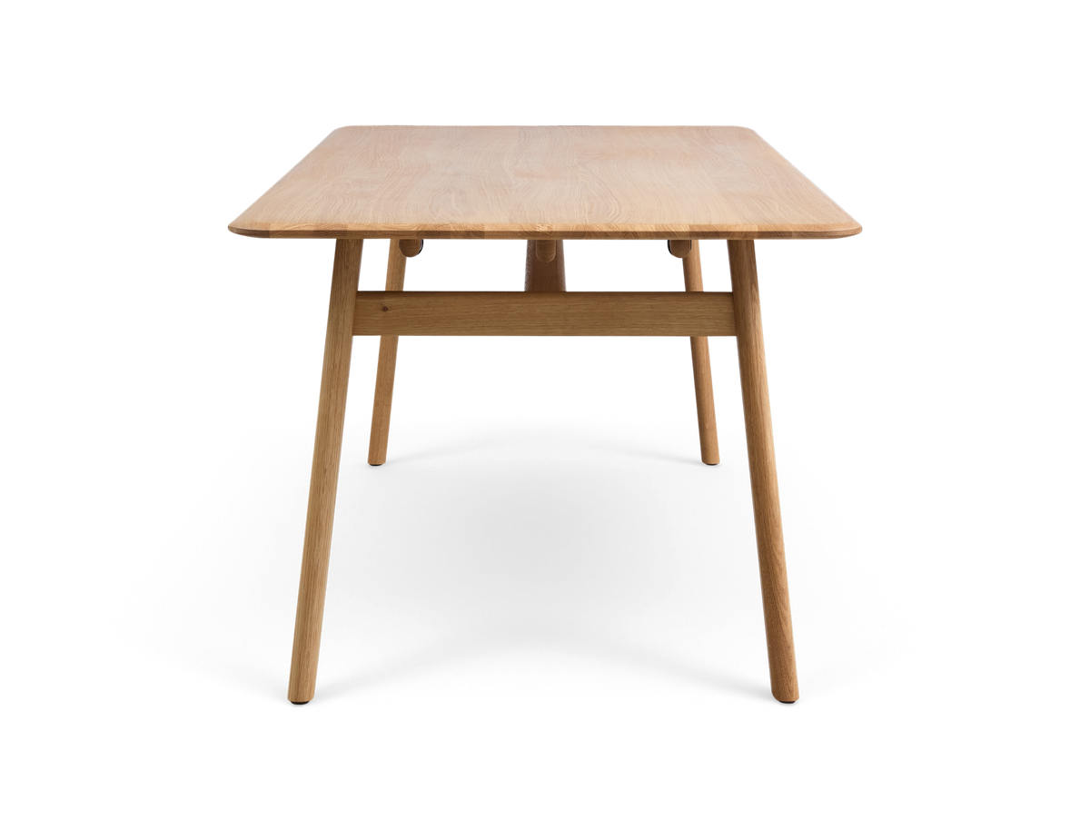 Rektangulært spisebord i lys eg med afrundede hjørner, frontvisning.