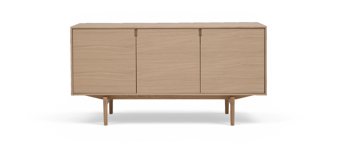 Lys eg-skænk med tre glatte låger på slanke ben i minimalistisk skandinavisk design.