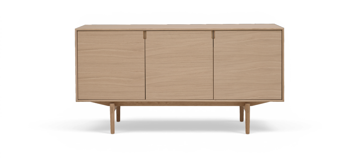 Lys eg-skænk med tre glatte låger på slanke ben i minimalistisk skandinavisk design.