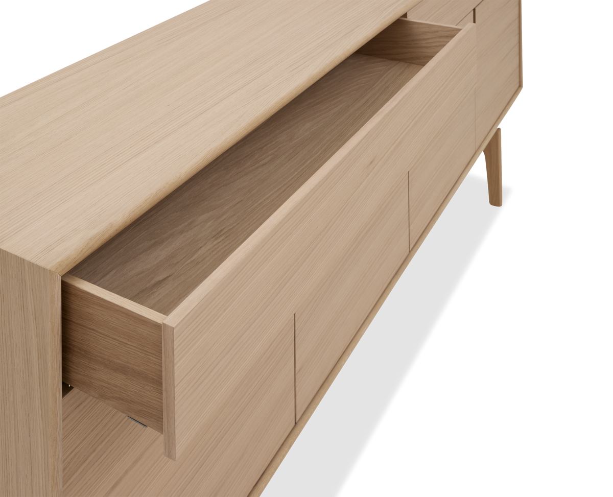 Lys egetræ sideboard med åben skuffe set i vinkel.