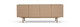 Minimalistisk skænk i lys eg med fire glatte låger på slanke ben, frontview, frilagt.
