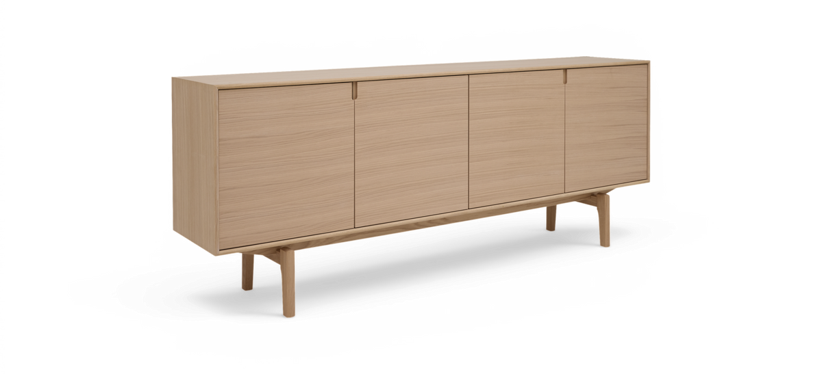 Lys egetræsskænk med fire låger på slanke ben i minimalistisk design, studiebillede på hvid baggrund.