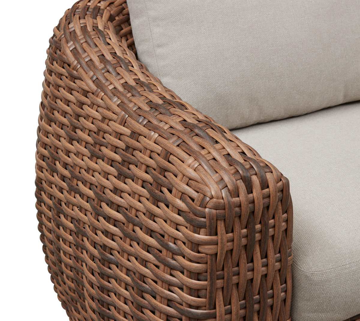 Nærbillede af flettet brunt rattan-armlæn på sofa med beige puder.
