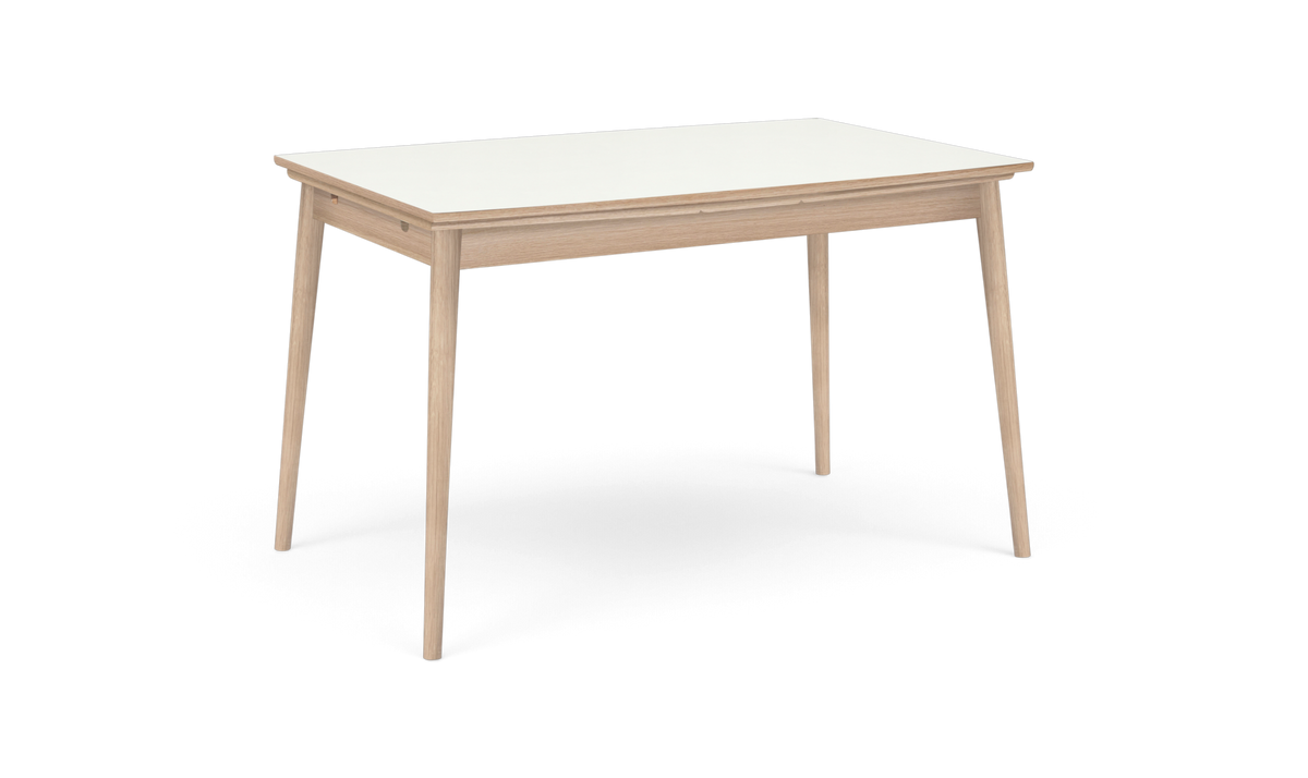 Rektangulært spisebord med hvid bordplade og lys egetræsramme med koniske ben, set i trekvart vinkel på hvid baggrund.