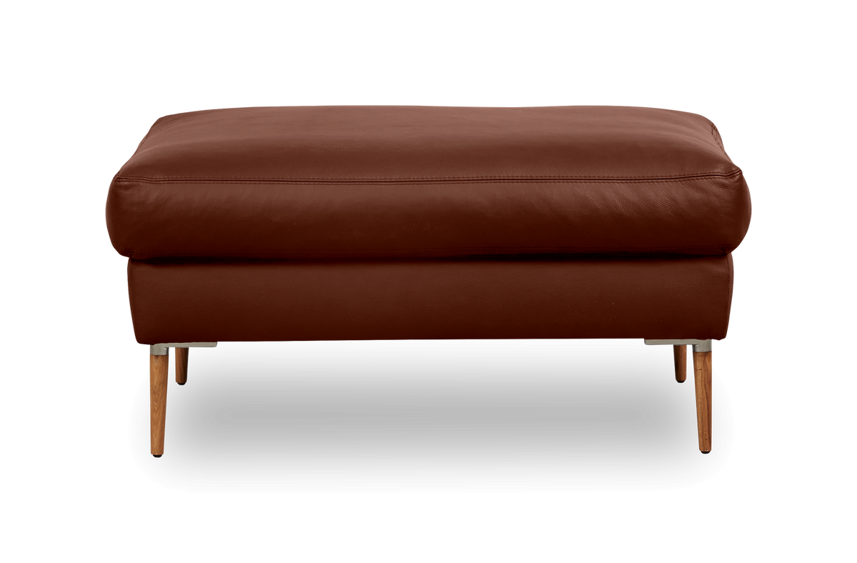 Brun læderpuf/ottoman med slanke træben set forfra på hvid baggrund.