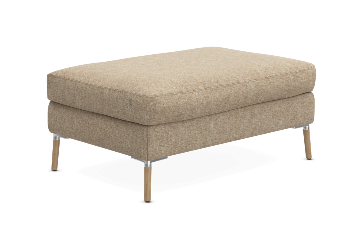 Beige puf/ottoman med stofbetræk og slanke ben i træ og metal.