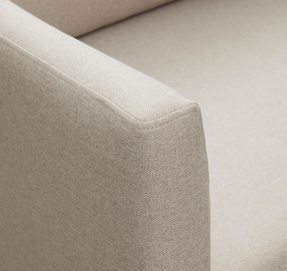 Nærbillede af beige sofa-armlæn og sæde i tekstureret stof.