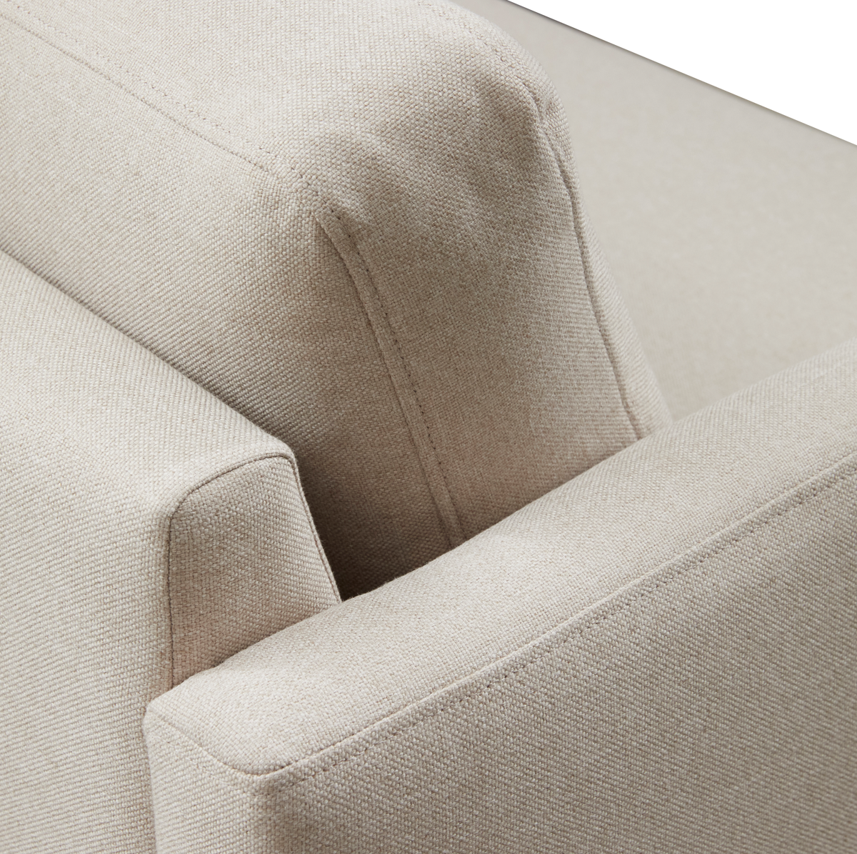 Nærbillede af beige stofsofa med armlæn og ryglæn, der viser den teksturerede polstring.