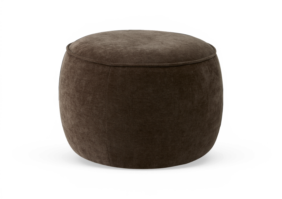 Rund mørkebrun polstret puf/ottoman i studie, med blød tekstil i velourlignende finish.