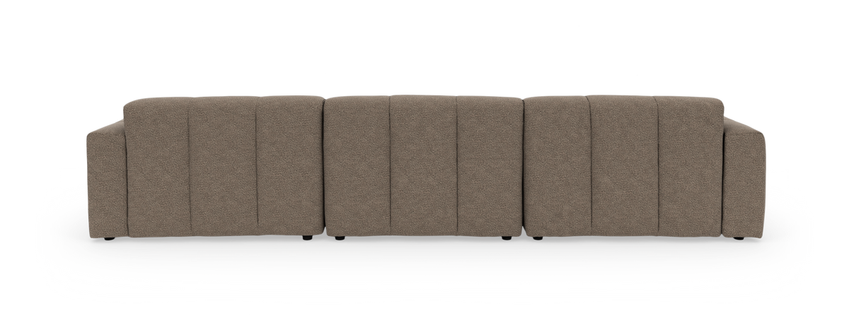 Brun modulsofa med chaiselong til højre, tuftet sæde og tykke puder på sort baggrund.