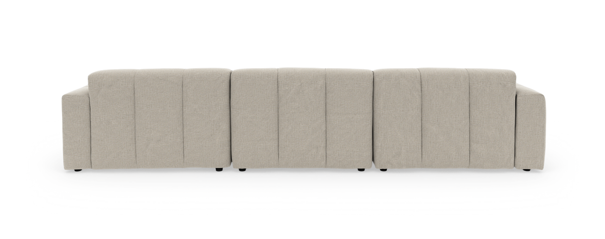 Lysebeige modulsofa med chaiselong til højre, tuftet og med bløde afrundede former, fritlagt på sort baggrund.