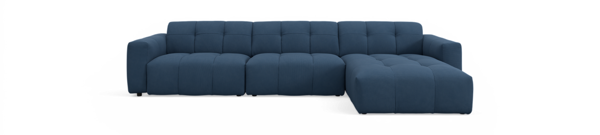 Blå modulsofa med højre chaiselong i studiemiljø på sort baggrund.