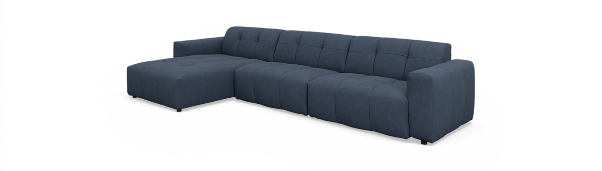 Mørkeblå modulsofa med venstrevendt chaiselong, tuftet og lav i moderne stil, frilagt på neutral baggrund.