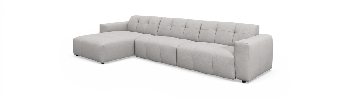 Lysegrå modulær hjørnesofa med venstrevendt chaiselong, blødt afrundede sæder og tuftede syninger, fritlagt på hvid baggrund.