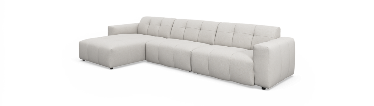 Lys beige L‑sofa med venstrevendt chaiselong, modulopbygget med bløde kanalquiltede puder og ret højre armlæn, frilagt på hvid baggrund.