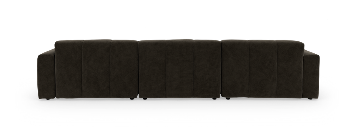 Beige modulsofa med chaiselong til venstre, dybe sæder og ribbet polstring, fritlagt på sort baggrund.
