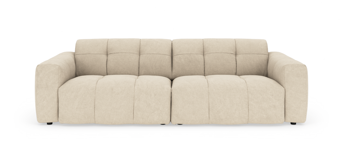 Beige modulsofa med brede armlæn og bløde, quiltede sæde- og ryghynder, fotograferet lige forfra på hvid studiobaggrund.