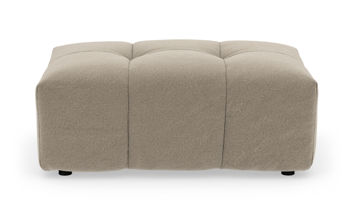 Beige polstret ottoman/fodpuf i stof, kvadratisk med bløde tuftede sektioner, isoleret på hvid baggrund.