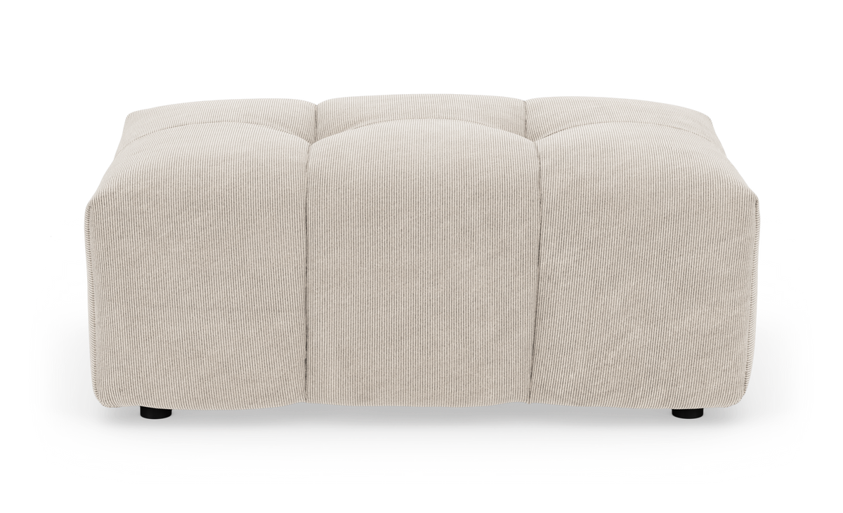 Beige kvadratisk puf/fodskammel i bredriflet fløjl med blødt afrundede kanter, set forfra på hvid baggrund.