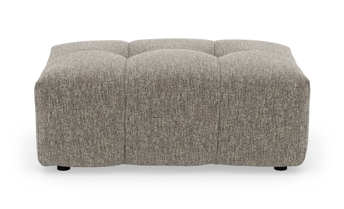 Kvadratisk polstret ottoman i grå‑beige tekstil, lav profil med tuftede sektioner set forfra.