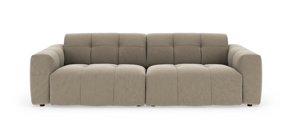 Beige modulsofa med brede armlæn og bløde, kvadratinndelte sædehynder, fotograferet lige forfra mod hvid baggrund.
