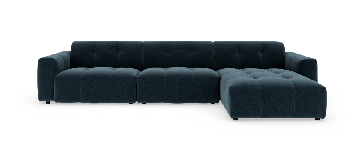 Modulær mørkeblå hjørnesofa med højrevendt chaiselong, lav profil og dybt tuftede, afrundede puder på hvid baggrund.