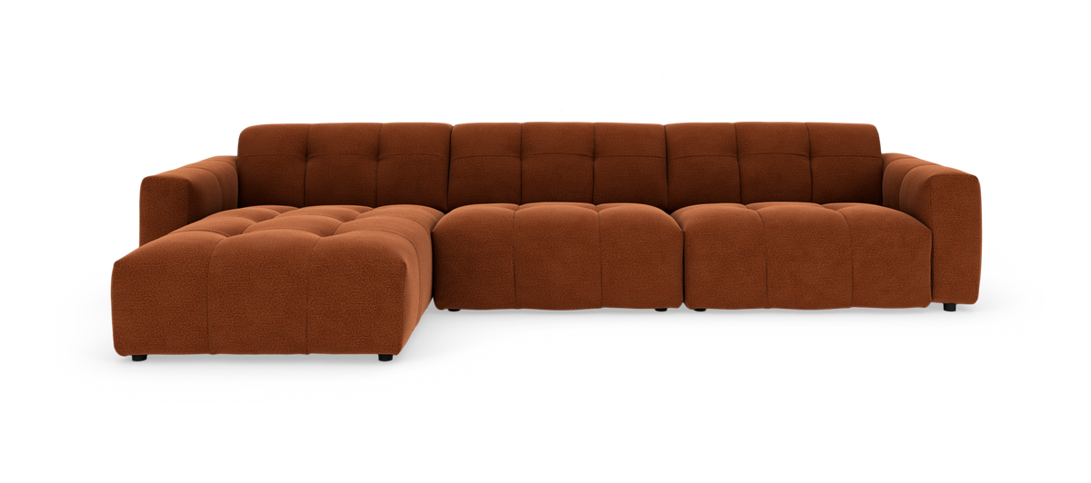 Modulsofa i rustorange stof med dybe, tuftede sædehynder og venstrevendt chaiselong, frilagt på hvid baggrund.