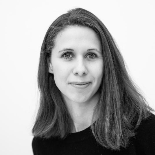 Sort-hvidt portræt af en person med skulderlangt hår og mørk trøje mod hvid baggrund.