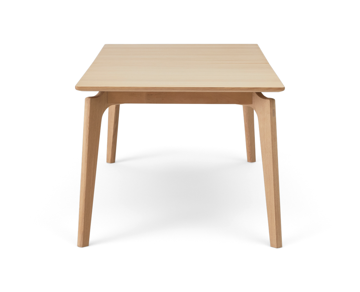 Forfra af et rektangulært bord i lys eg med fire tilspidsede ben.