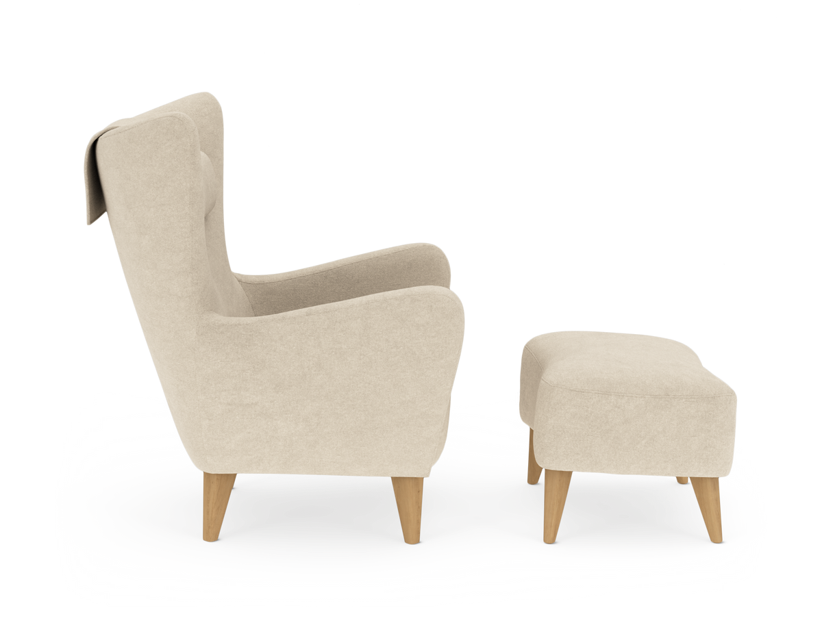 Beige lænestol med matchende fodskammel set fra siden, træben, på hvid baggrund.