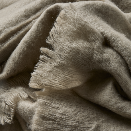 Nær detalje af blød, lodden beige plaid med frynset kant.