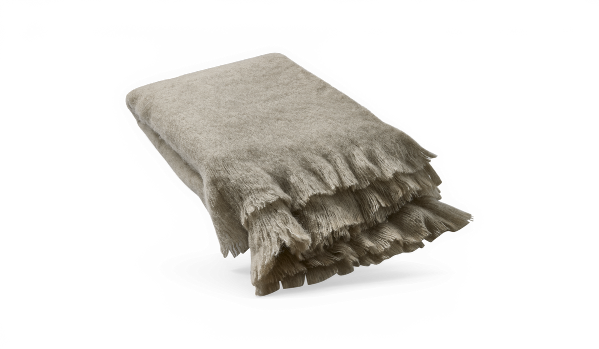 Sammenfoldet beige plaid med bløde frynser på mørk baggrund.