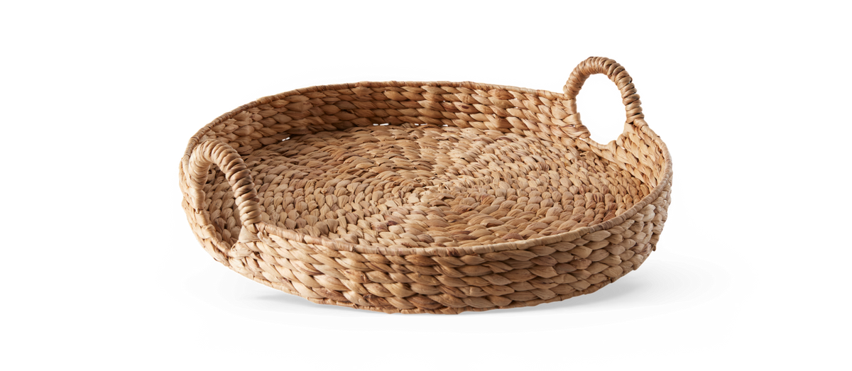 Rund flettet bakke i naturmateriale med to håndtag, frilagt på hvid baggrund.