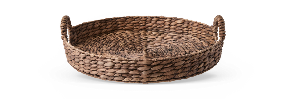 Rund flettet bakke/kurv i naturmaterial med to håndtag på sort baggrund.