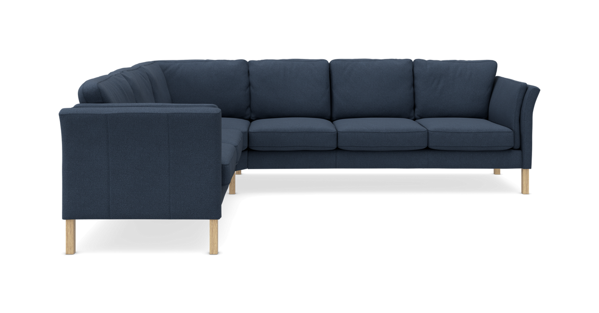 Mørkeblå L‑formet hjørnesofa med træben på hvid baggrund.