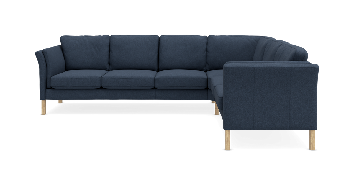 Mørkeblå L-formet sofa med fire sædehynder og træben.