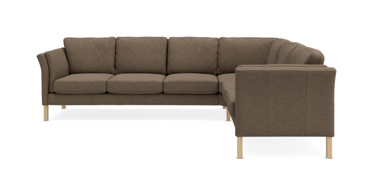 Brun L‑formet modulsofa med træben på frilagt baggrund.
