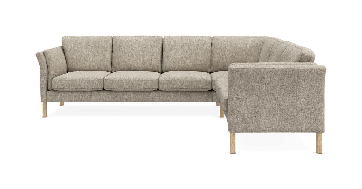 Beige L-formet stofsofa med træben, set forfra mod hvid baggrund.