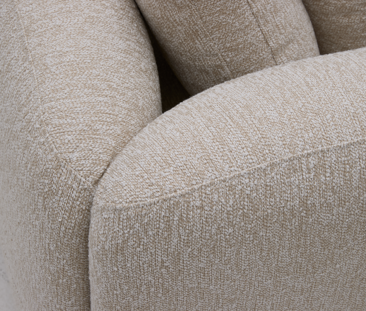 Nærbillede af en rund beige bouclésofa med tekstureret polstring og bløde puder.