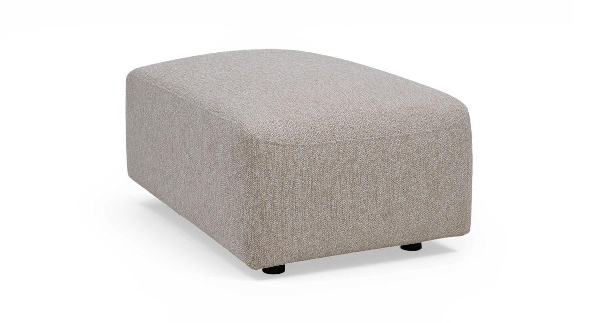 Beige stofbetrukket ottoman/puf i rektangulær form med blødt afrundede hjørner, frilagt mod hvid baggrund.