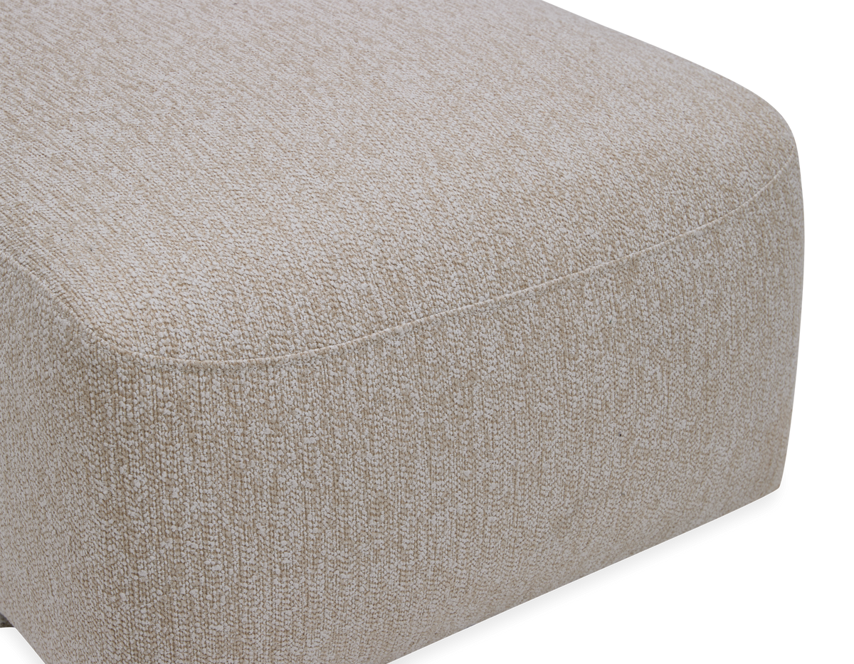 Beige, tekstureret firkantet puff/ottoman med afrundede hjørner, fritlagt produktfoto.