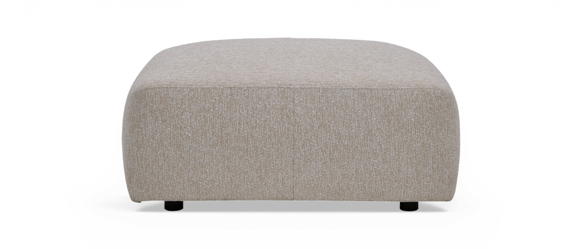 Beige firkantet puf/ottoman i stof med afrundede hjørner, set forfra.